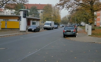 Blick auf die Sven-Hedin-Str. und den Kindergarten. Davor, beidseitiges Parken von Kraftfahrzeugen auf den Gehwegen.